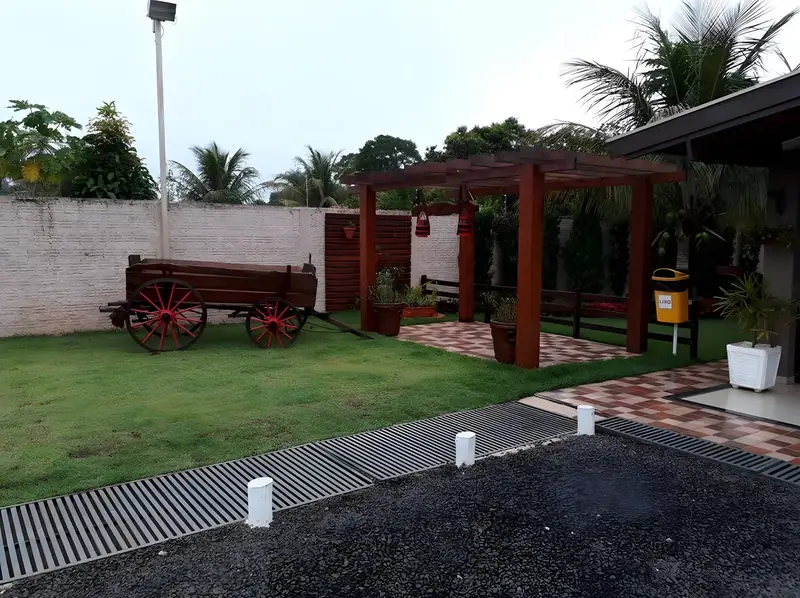 Carro de boi decorativo e pérgola no jardim ao entardecer