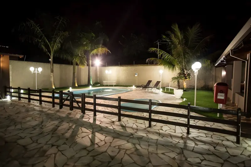 Piscina à noite com luminárias acesas e cerca de madeira