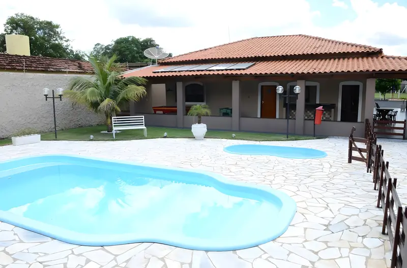 Piscina adulto e piscina infantil em frente à casa principal, com gramado e palmeira
