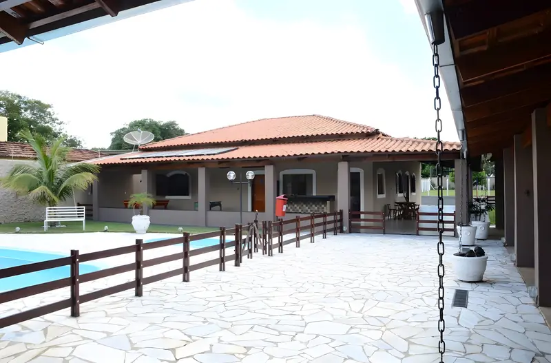 Piscina cercada por deque de pedra com a casa principal ao fundo