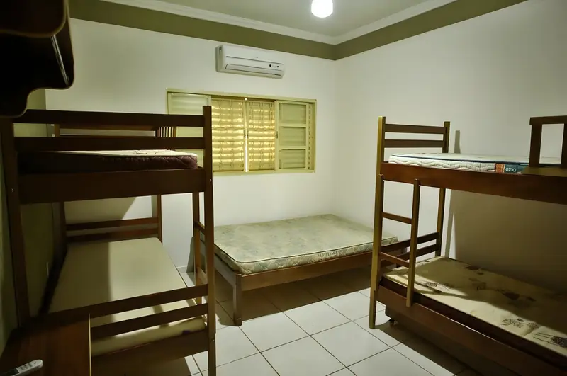 Suíte com cama de casal entre dois beliches de madeira e ar-condicionado